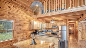 L’intérieur d’un chalet en bois comprend un coin repas, une cuisine et un balcon.