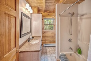 Une salle de bain rustique, aménagée dans une cabane en bois, avec un lavabo, un miroir et une douche.