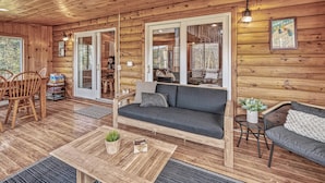 L’intérieur d’un chalet accueillant, avec un plancher en bois, un canapé, une table à manger et une chaise.