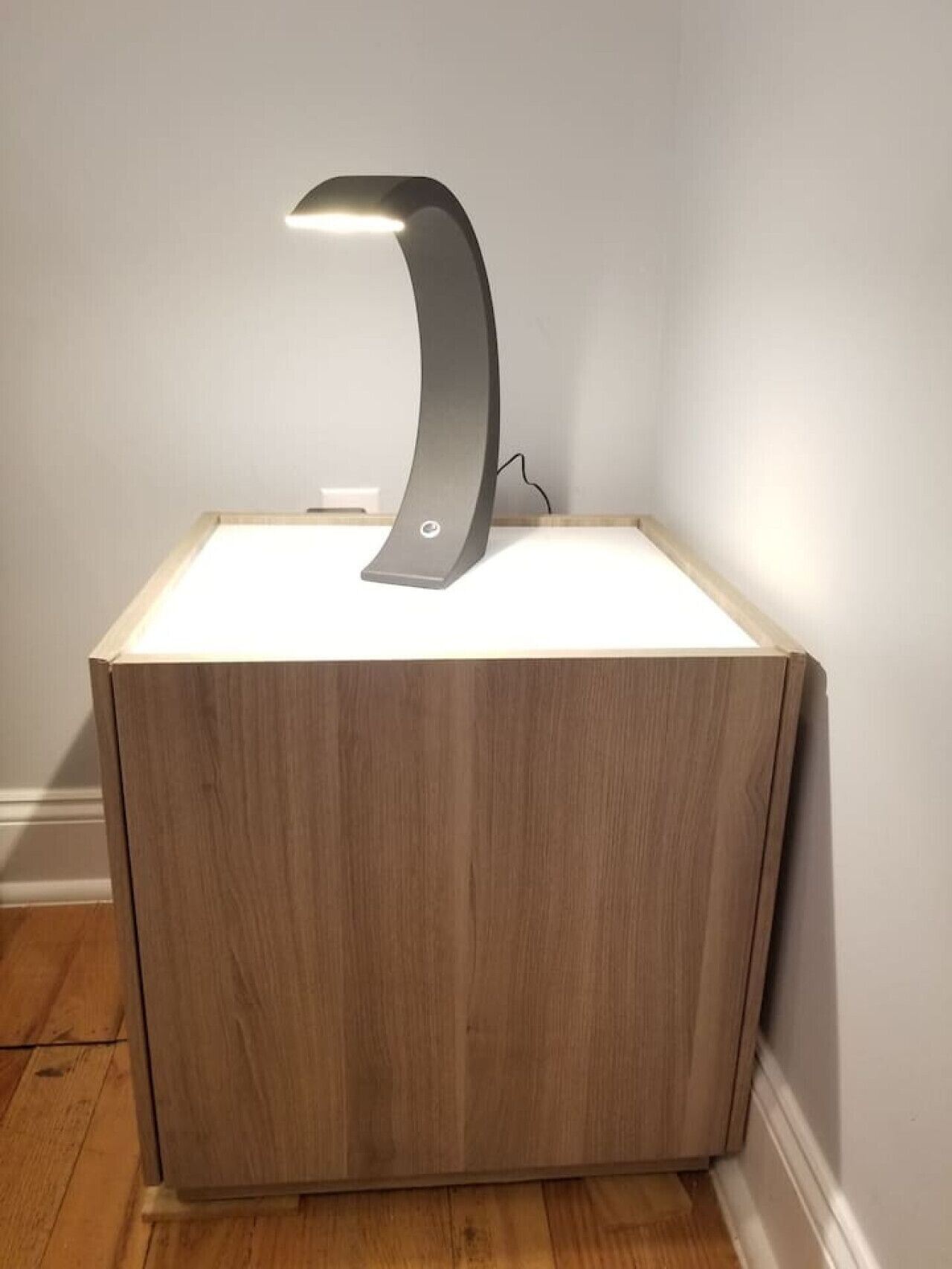 A modern, minimalist bedside table with a built-in lamp.