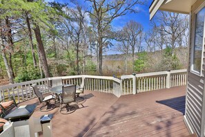 A wooden deck with outdoor furniture, a white railing, and a view of trees and a body of water. - Spacious Lake House for Large Groups w Private Acre+ short path to Lake (Barnstable)