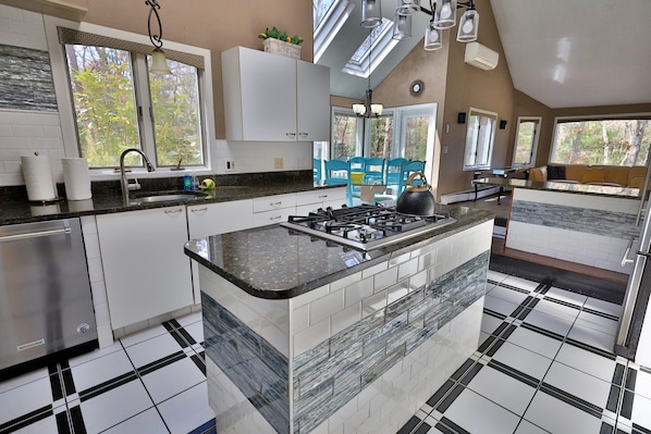 A kitchen with a central island, white cabinets, a gas stove, and a sink.