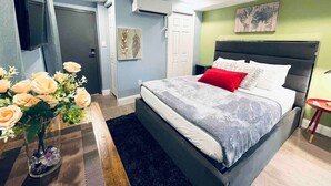 Una camera da letto con un letto, un comodino, un vaso con fiori e una TV a parete.