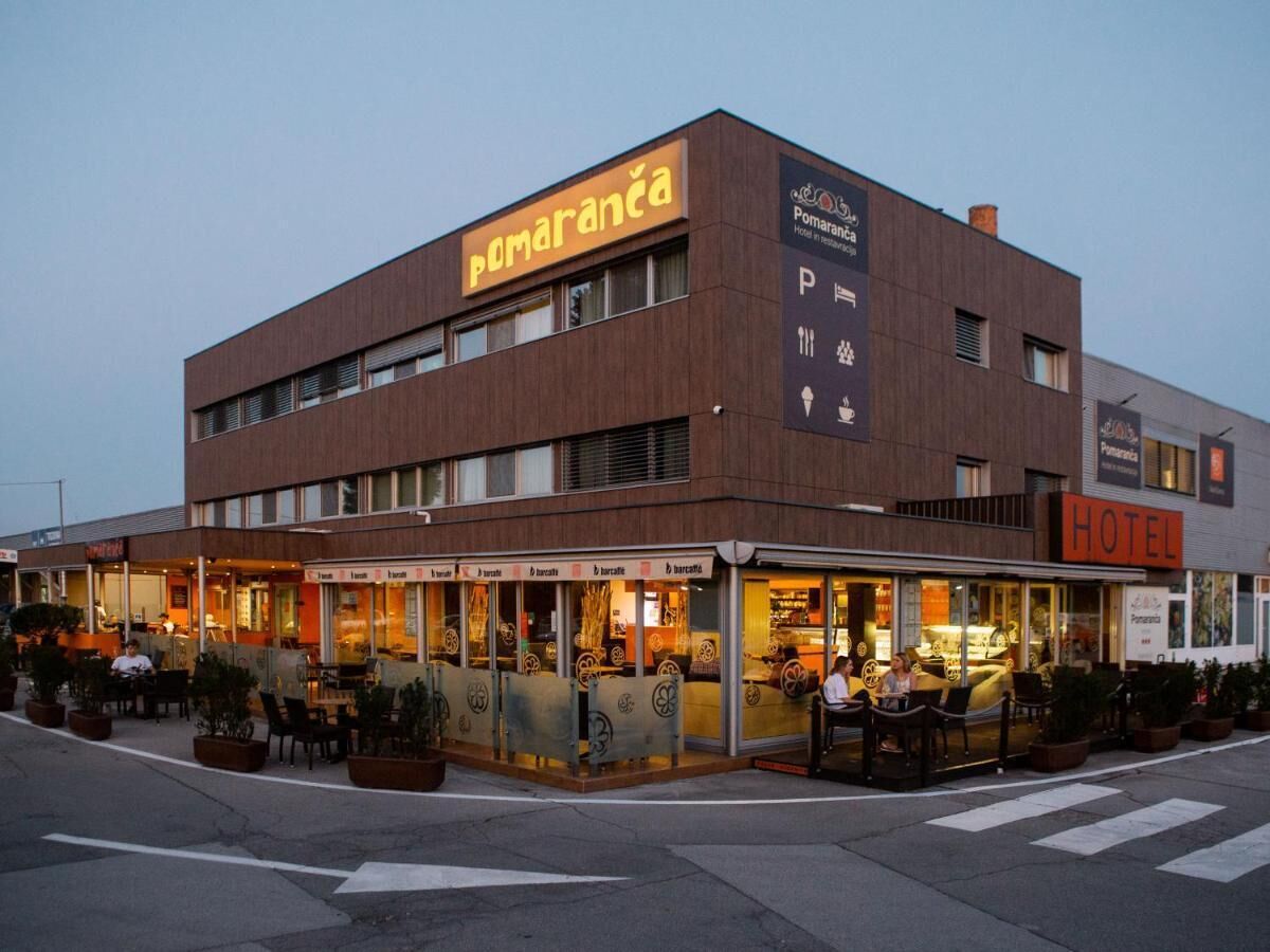 A hotel with a modern design, featuring a prominent 'Pomaranca' sign and a 'HOTEL' sign.