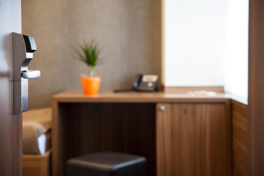 A modern room with a wooden desk, a small stool, and a potted plant.