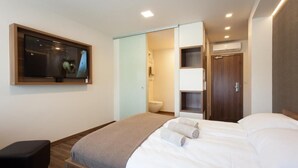 A modern hotel room with a bed, a TV, a wardrobe, and a bathroom. - Hotel Pomaranča (Ptuj)