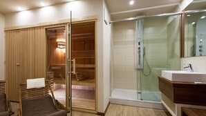 A modern bathroom with a glass-enclosed shower, wooden bath area, and a wooden bench. - Hotel Pomaranča (Ptuj)