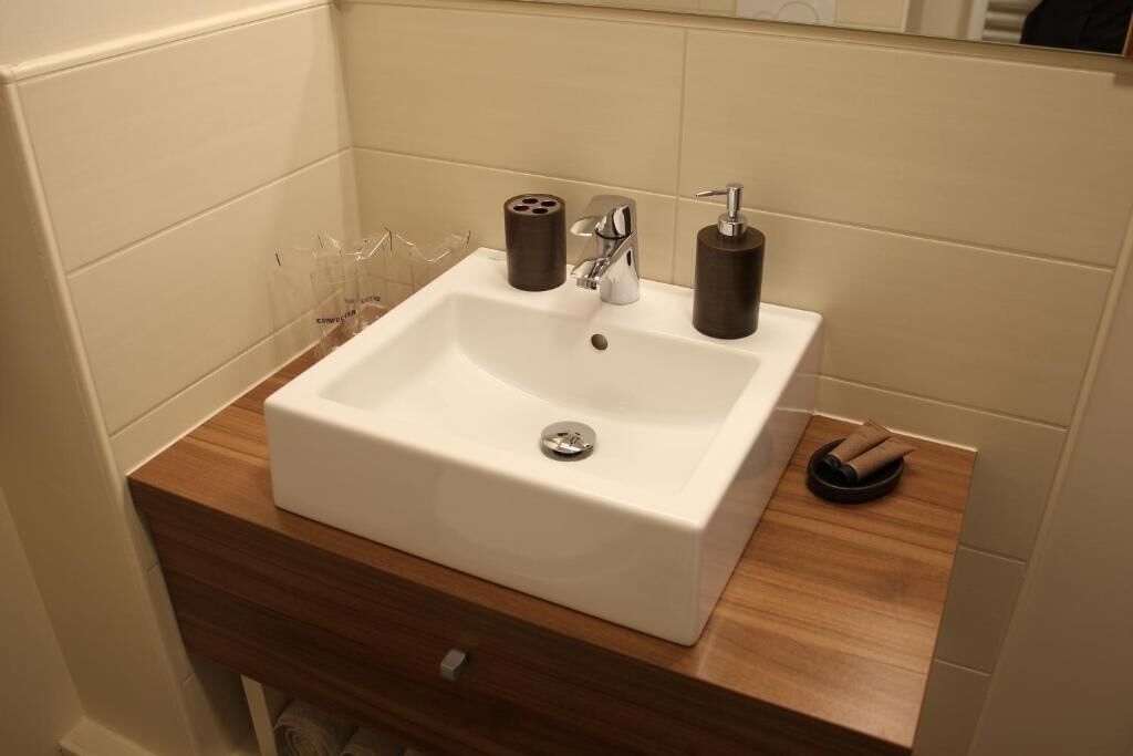 Un baño con lavamanos blanco, encimera de madera y un espejo encima.