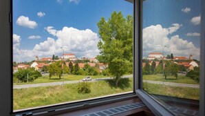 A view from a window overlooking a town with red-roofed buildings and a clear sky. - Hotel Pomaranča (Ptuj)