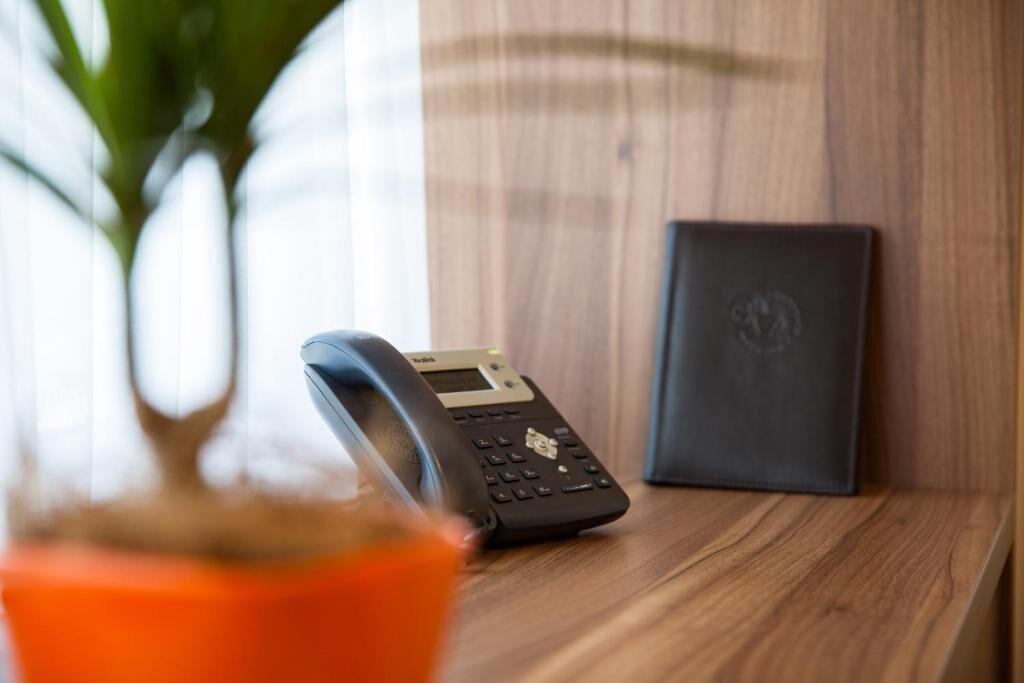 Um telefone sobre uma superfície de madeira, com uma caixa preta ao lado.