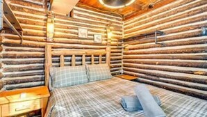 A log cabin room with a bed, a nightstand, and a ceiling fan.