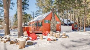 A cabin with a red exterior, surrounded by snow and trees.