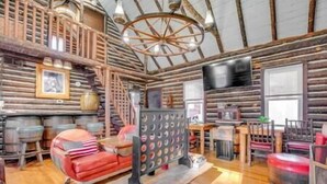 A rustic log cabin interior with a wooden staircase, a red sofa, and a wall-mounted circular object.