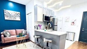 Een moderne keuken met witte kasten, roestvrijstalen apparatuur en een bar met krukken.
