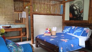 Una habitación con una cama, un banco de madera, una mesita y un estante en la pared.