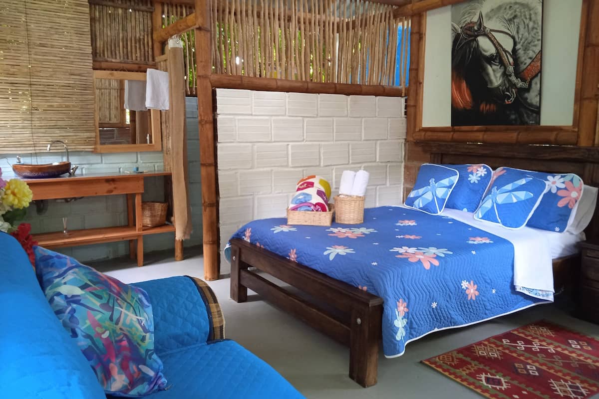 Een kamer met een bed, een houten bankje, een klein tafeltje en een wandplank.