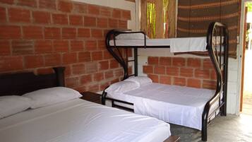Una habitación con dos literas, una pared de ladrillo y un ventanal con cortinas.