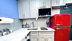 A kitchen with white cabinets, a red refrigerator, a washing machine, and a microwave. - New! Suite nearby Rittenhouse Square (Philadelphia)