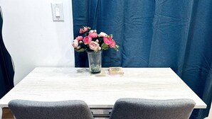 A dining table with two grey chairs, a vase with pink flowers, and a small book on the table. - New! Suite nearby Rittenhouse Square (Philadelphia)