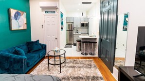 A compact living space with a teal sofa, a small round table, and a kitchenette area. - New! Suite by Rittenhouse Square! (Philadelphia)