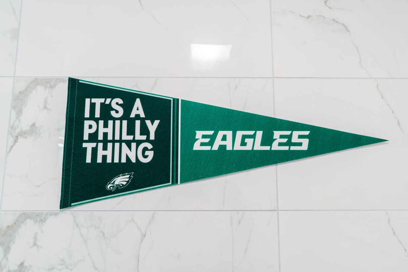 A pennant with "IT'S A PHILLY THING" and "EAGLES" on a white marble floor.