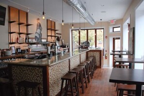 A modern bar area with a long counter, stools, and a patterned wall. - Modern Cozy Huge Balcony in Heart of Passyunk (Philadelphia)