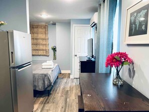 A compact hotel room with a bed, a small table, a refrigerator, a TV, and a vase with flowers. - Rittenhouse Square close by Kimmel Center Suite (Philadelphia)