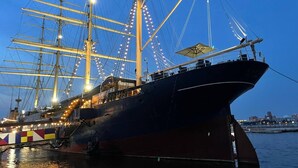 Un grand navire a accosté dans un port, arborant de nombreux mâts et une complexité de cordages.
