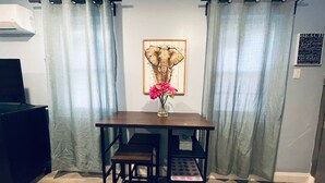 Un petit coin repas avec une table et des chaises, un vase de fleurs et un tableau accroché au mur.
