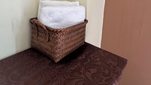 Un coin avec un panier en osier contenant une serviette blanche, posé sur une table marron à motifs.