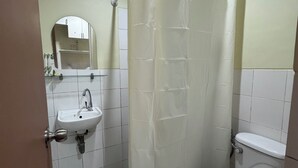 Une salle de bain avec un lavabo blanc, un miroir, des toilettes et un rideau de douche.