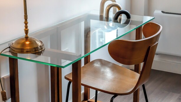 A dining area with a glass table, two chairs, a lamp, and a modern kitchen in the background. - City Life in Style: Chic Studio in Prime Area (London)