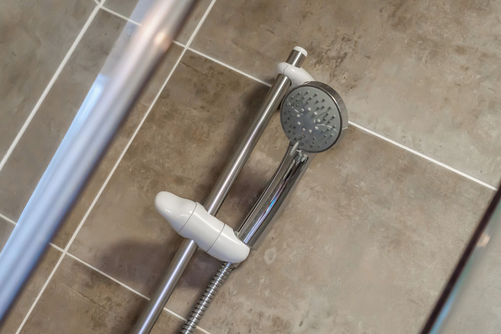 A shower with a handheld showerhead and a handheld control.