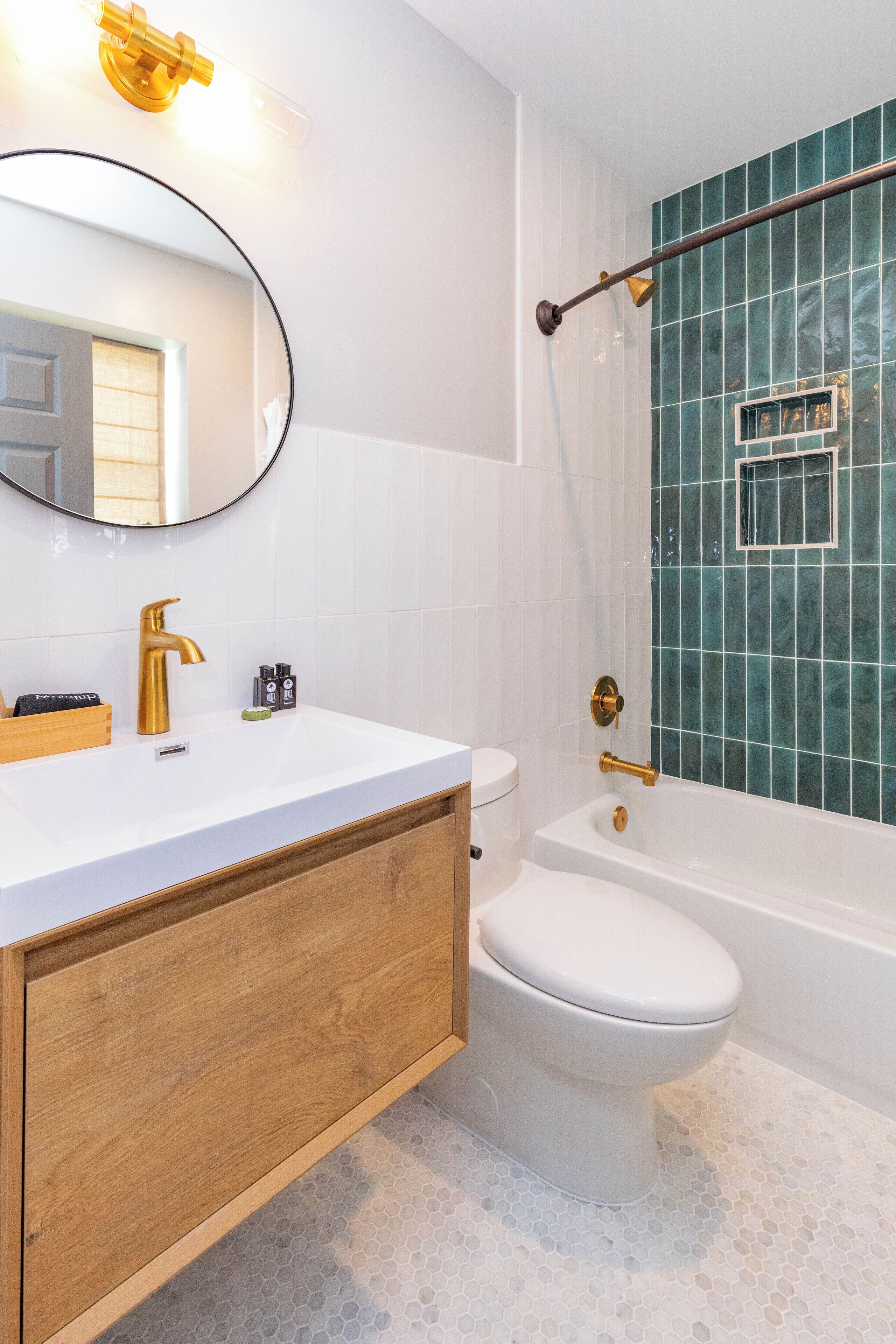 A bathroom with a white sink, gold faucet, and a wooden vanity.