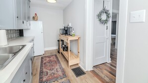 A modern kitchen with white cabinets, a coffee machine, and a wooden shelf. - Whispering WillowBnB – Cozy Central Stay Near IUP in Indiana, PA (Indiana)