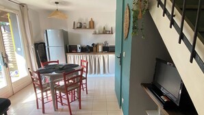 Una cucina moderna con frigorifero, fornello e microonde. C'è un'area pranzo con tavolo e sedie. Un televisore è montato a parete.