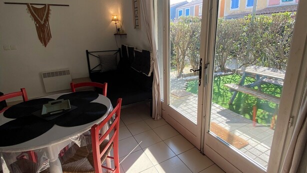 Zona pranzo con tavolo e sedie, un divano e una porta vetrata scorrevole che dà su un patio esterno.