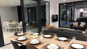 Uma sala de jantar moderna com uma mesa comprida posta para seis pessoas, rodeada por cadeiras pretas.