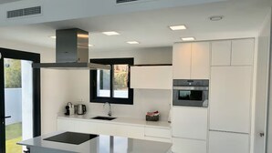 Cozinha moderna com ilha central, forno embutido e janela com vista para um jardim.