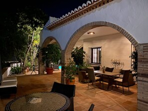 Un patio con una mesa redonda, sillas y plantas en macetas.