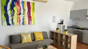 Una sala de estar moderna con un sofá gris, cojines amarillos, una mesa de centro de madera y un cuadro abstracto colorido.