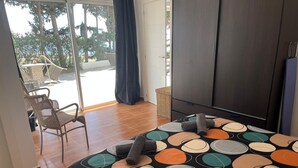 Un dormitorio con cama, una silla, un armario y vistas al exterior.