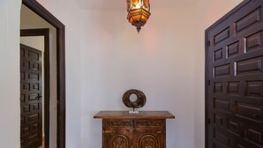Un couloir avec une armoire en bois, un luminaire décoratif et deux portes.