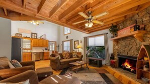 A cozy living room with a fireplace, wooden ceiling beams, and a stone wall. - Talking Waters - Fishing Camp (Blue Ridge)