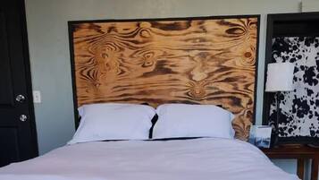 A neatly made bed with white bedding, a wooden headboard, and a patterned carpet.