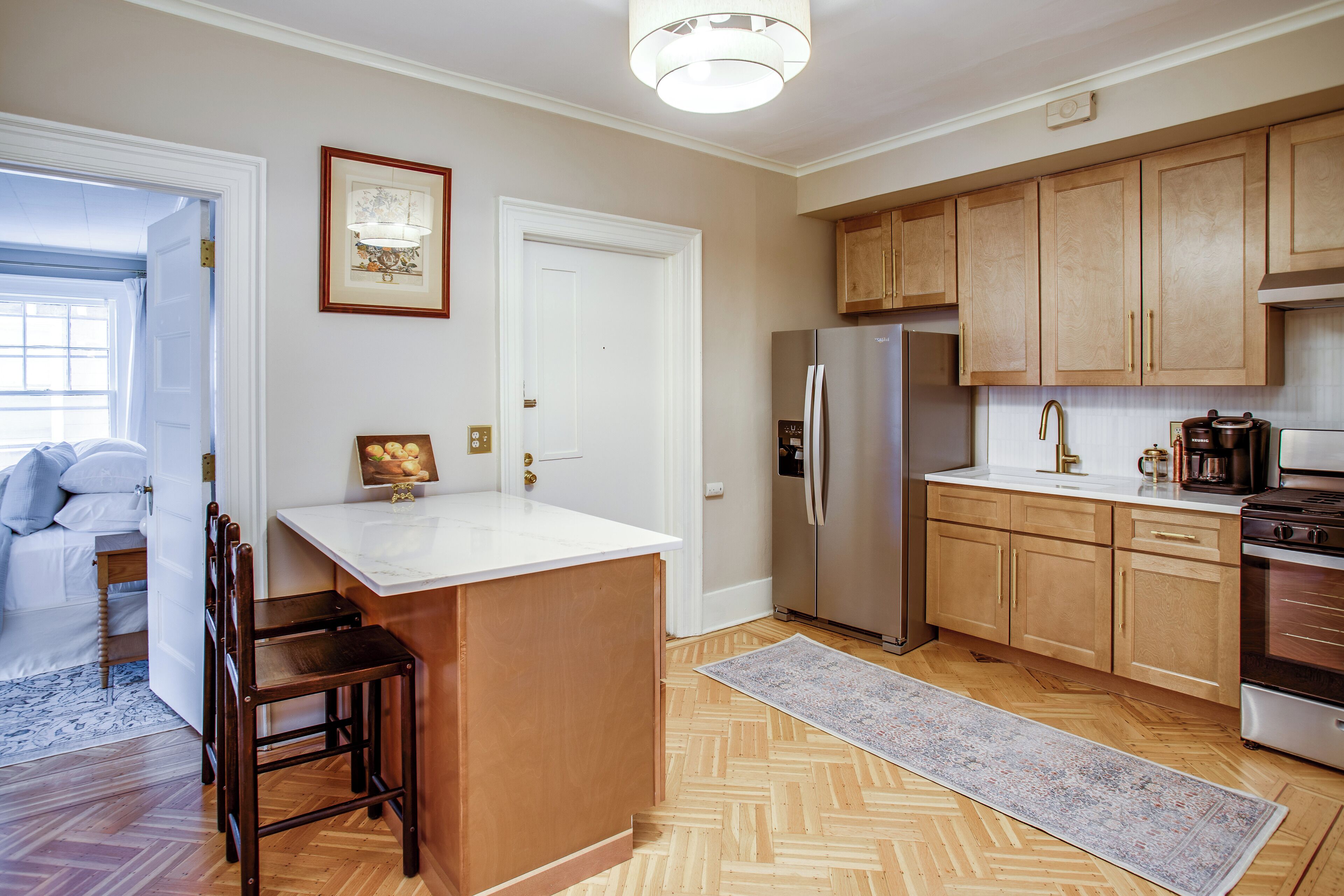 A modern kitchen with wooden cabinets, a stainless steel refrigerator, and a large island.
