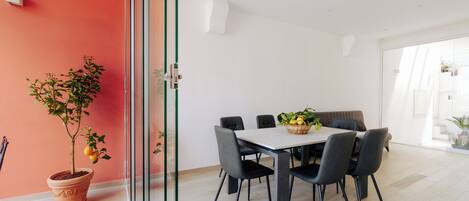 A modern dining area with a glass partition, a potted plant, and a table with chairs.
