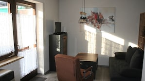 Una sala de estar con una silla marrón, un sofá oscuro, una mesa de madera y un cuadro en la pared.