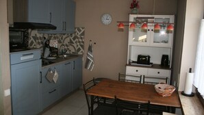 Una cocina compacta con armarios azules, una mesa de madera y un reloj en la pared.
