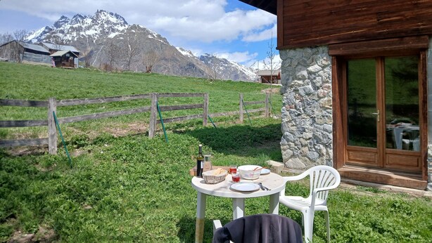 Una cabaña de madera con un muro de piedra y una mesa dispuesta con platos, una botella y una cesta.
